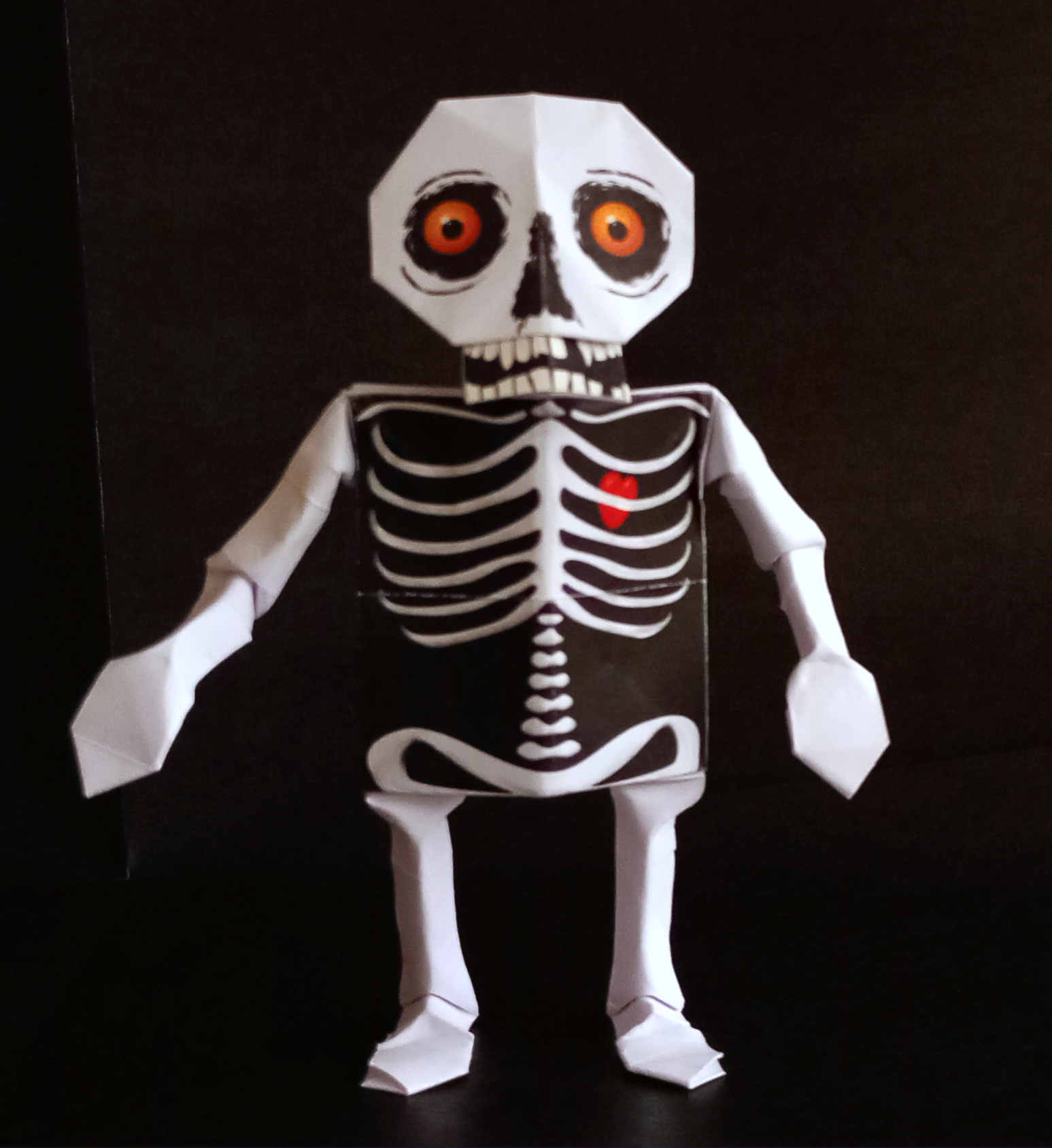 An orogami skeleton with orange eyes and a red heart visible behind its ribs

