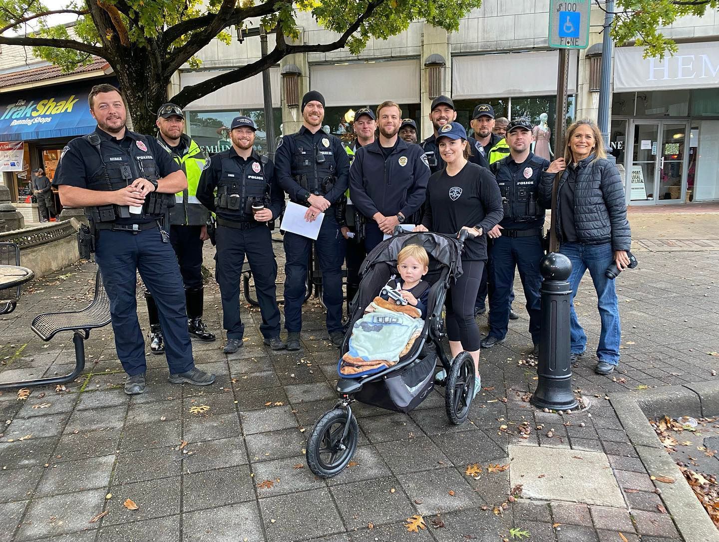 A group of police officers are posing for a picture with a baby in a stroller.