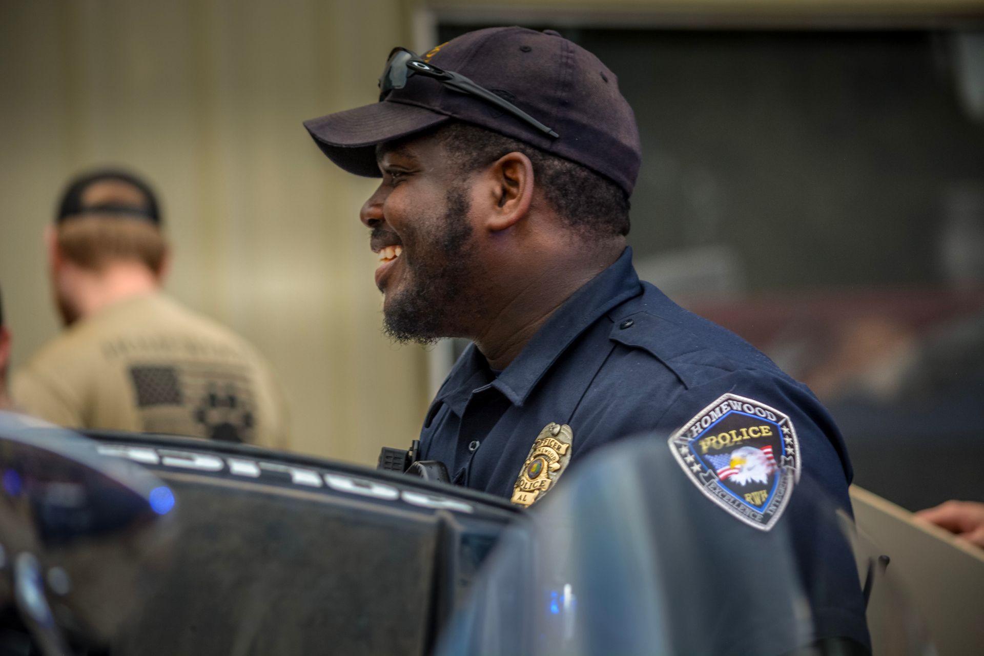 A police officer is standing next to a motorcycle and smiling.
