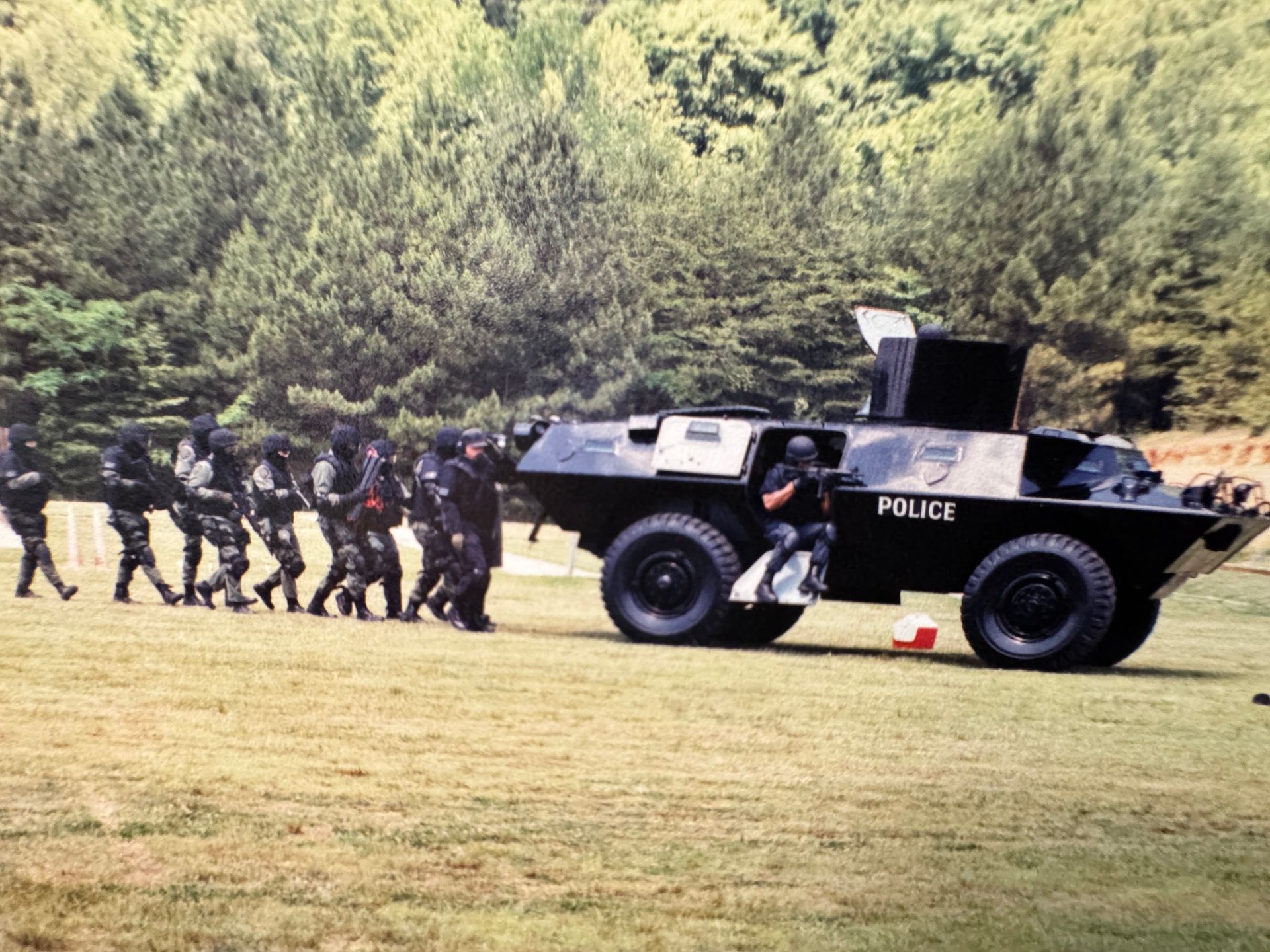 A group of soldiers are walking in front of a police vehicle