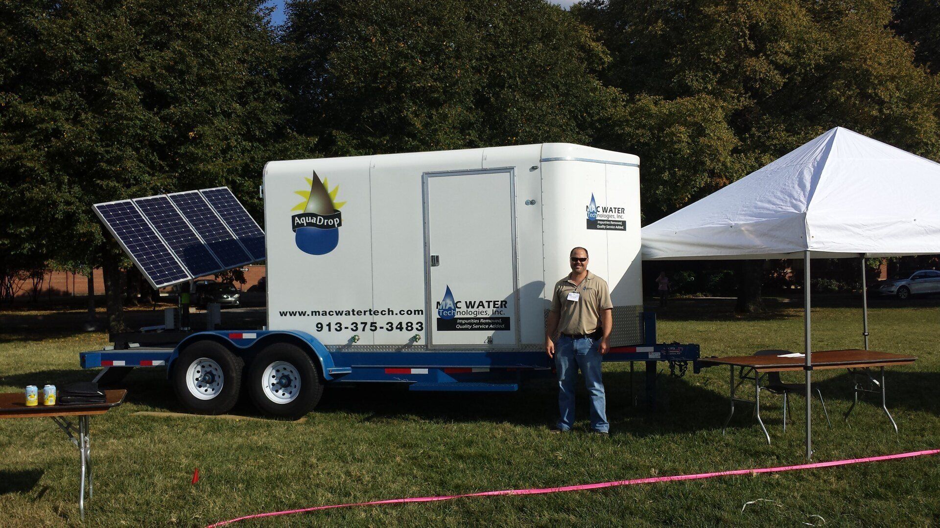 A man stands in front of a trailer with a solar panel on it