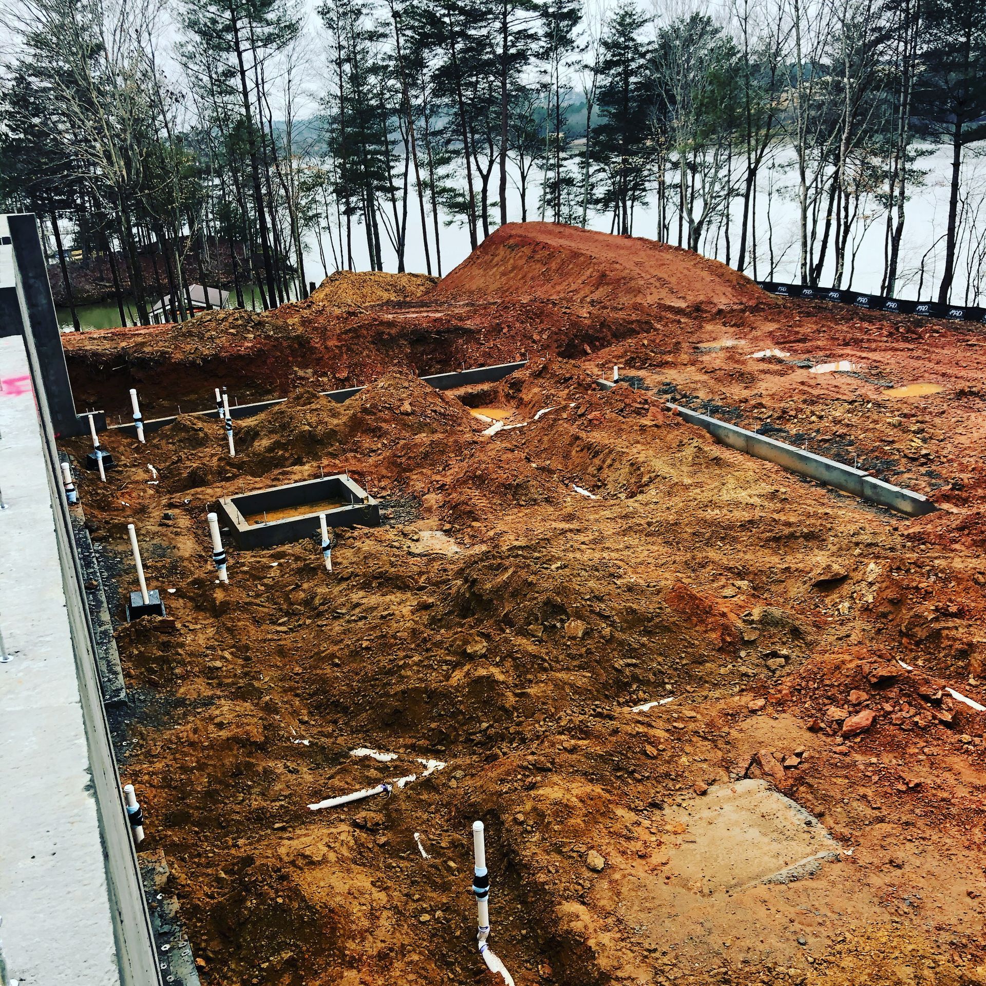 A construction site with a lot of dirt and trees in the background.