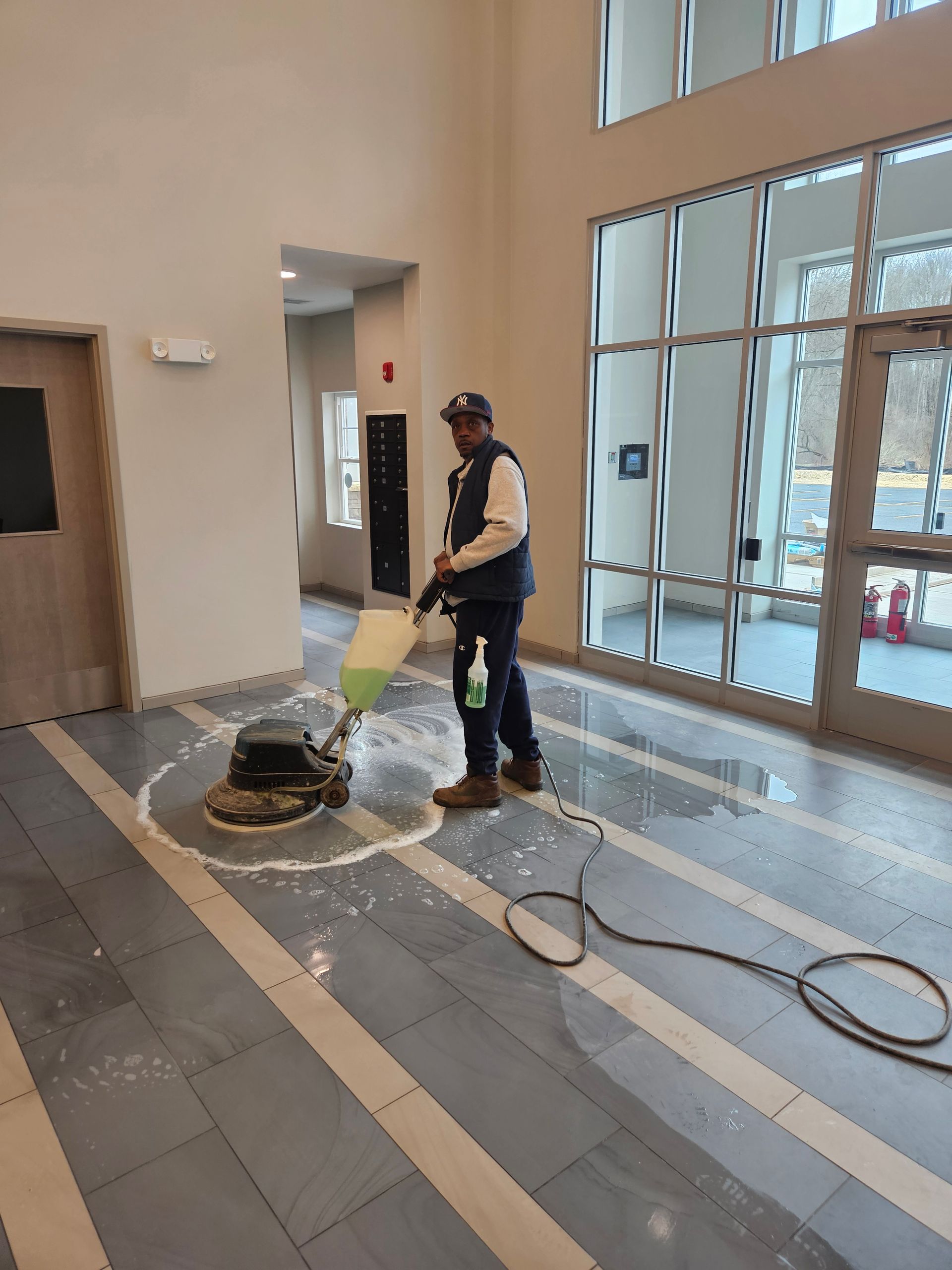 A floor sander moves across a parquet floor, showing the contrast between the worn, original finish and the sanded wood.