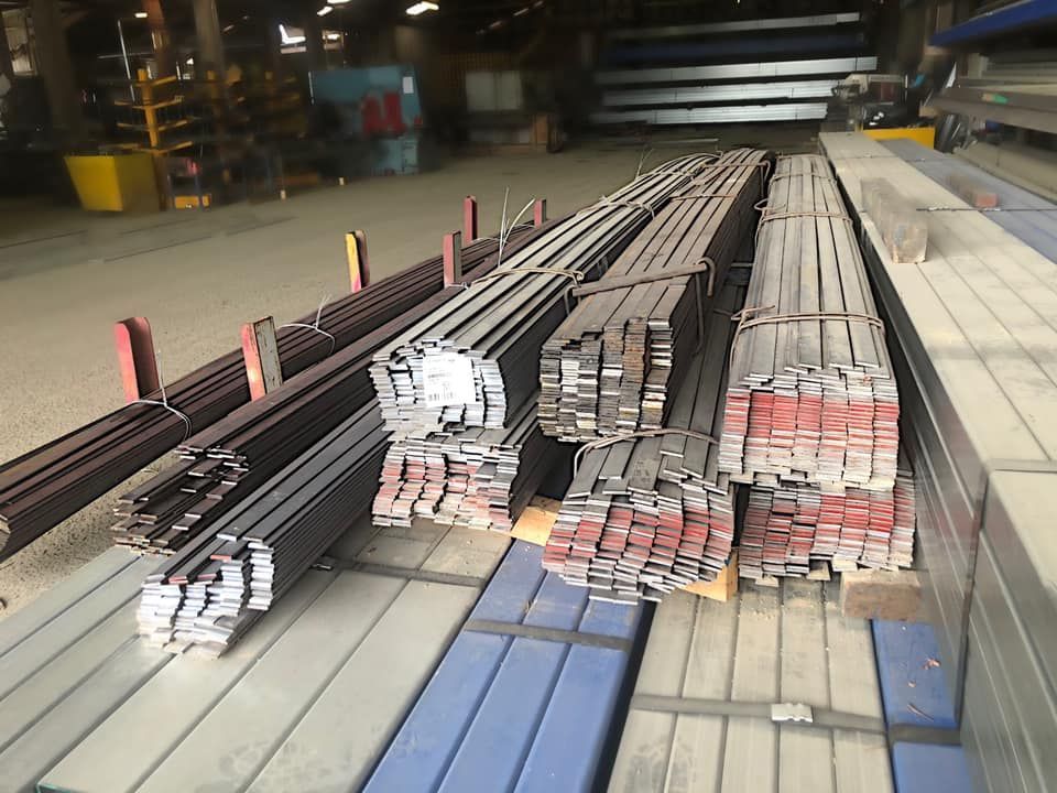 Bundles of Dark Gray Metal Bars Stored in an Industrial Warehouse Setting — Ingham Agencies in Ingham, QLD