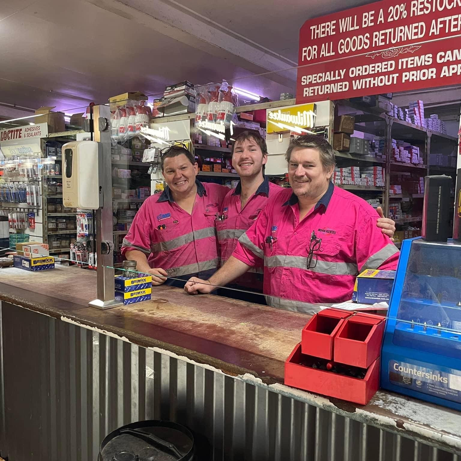Three People in Matching Pink Button-up Work Shirts Stand Behind a Counter — Ingham Agencies in Ingham, QLD