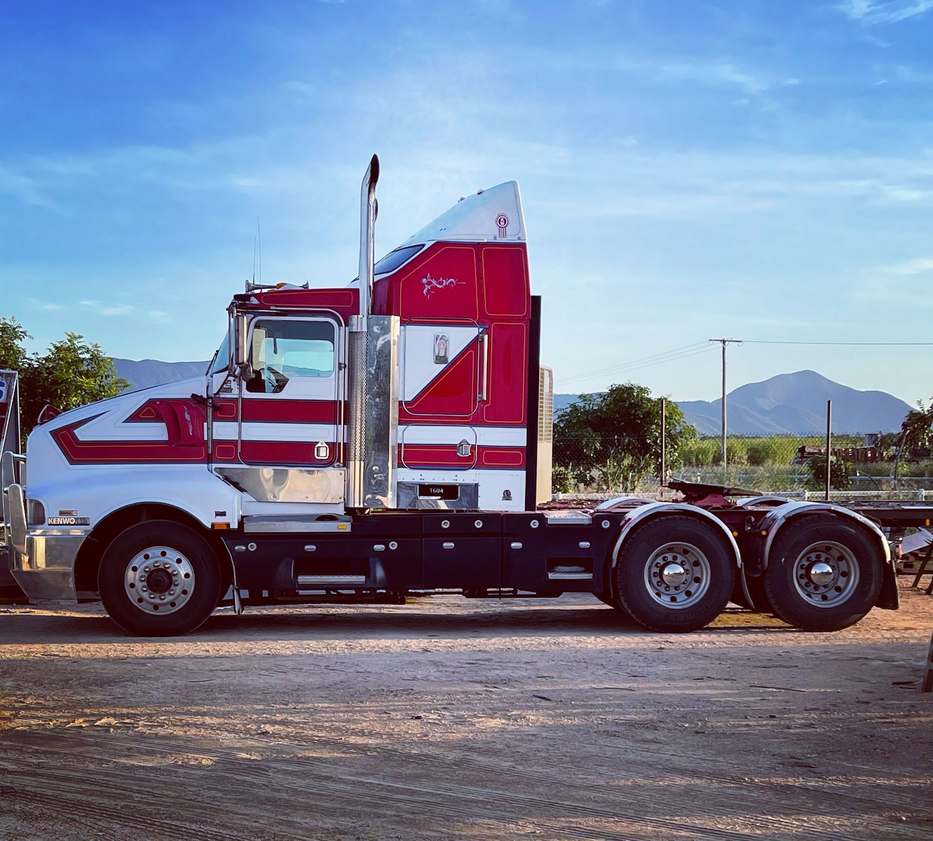 Red and white semi-truck parked on a gravel lot under a blue sky. — Ingham Agencies in Ingham, QLD