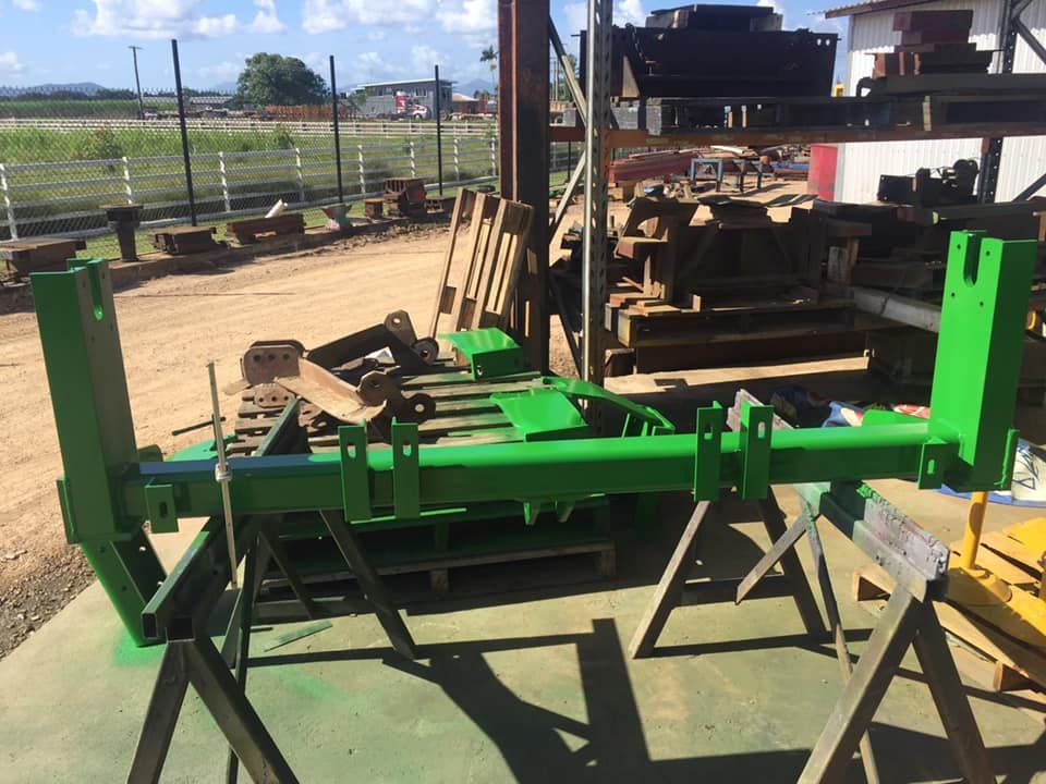 A Bright Green, Metal Tractor Attachment Frame Sits on Two Sawhorses — Ingham Agencies in Ingham, QLD
