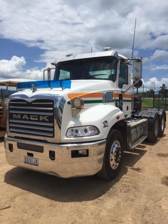 White Mercedes flatbed truck parked on a gravel lot under a clear blue sky — Ingham Agencies in Ingham, QLD