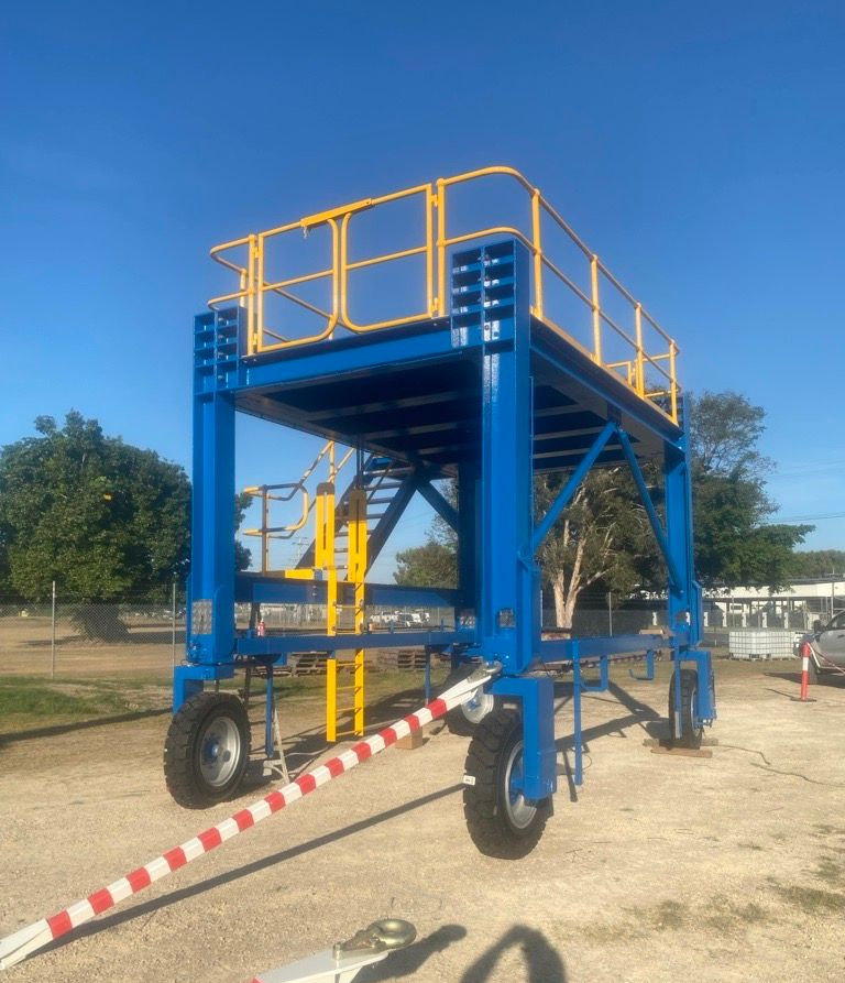 Blue elevated maintenance platform with yellow railings and stairs in a dry outdoor area — Ingham Agencies in Ingham, QLD
