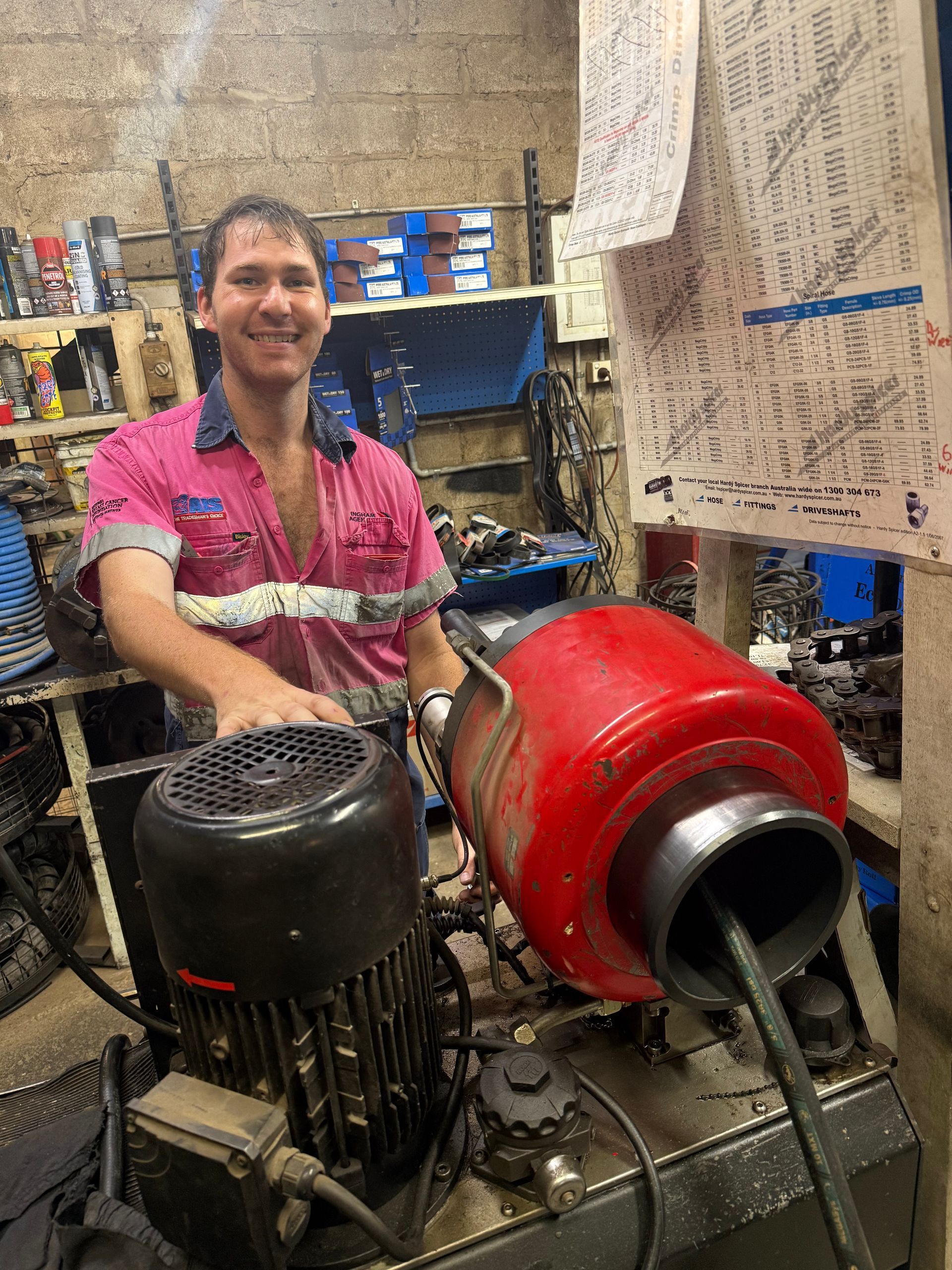 Person smiling beside industrial machinery in a workshop, with red and black equipment in the foreground  — Ingham Agencies in Ingham, QLD