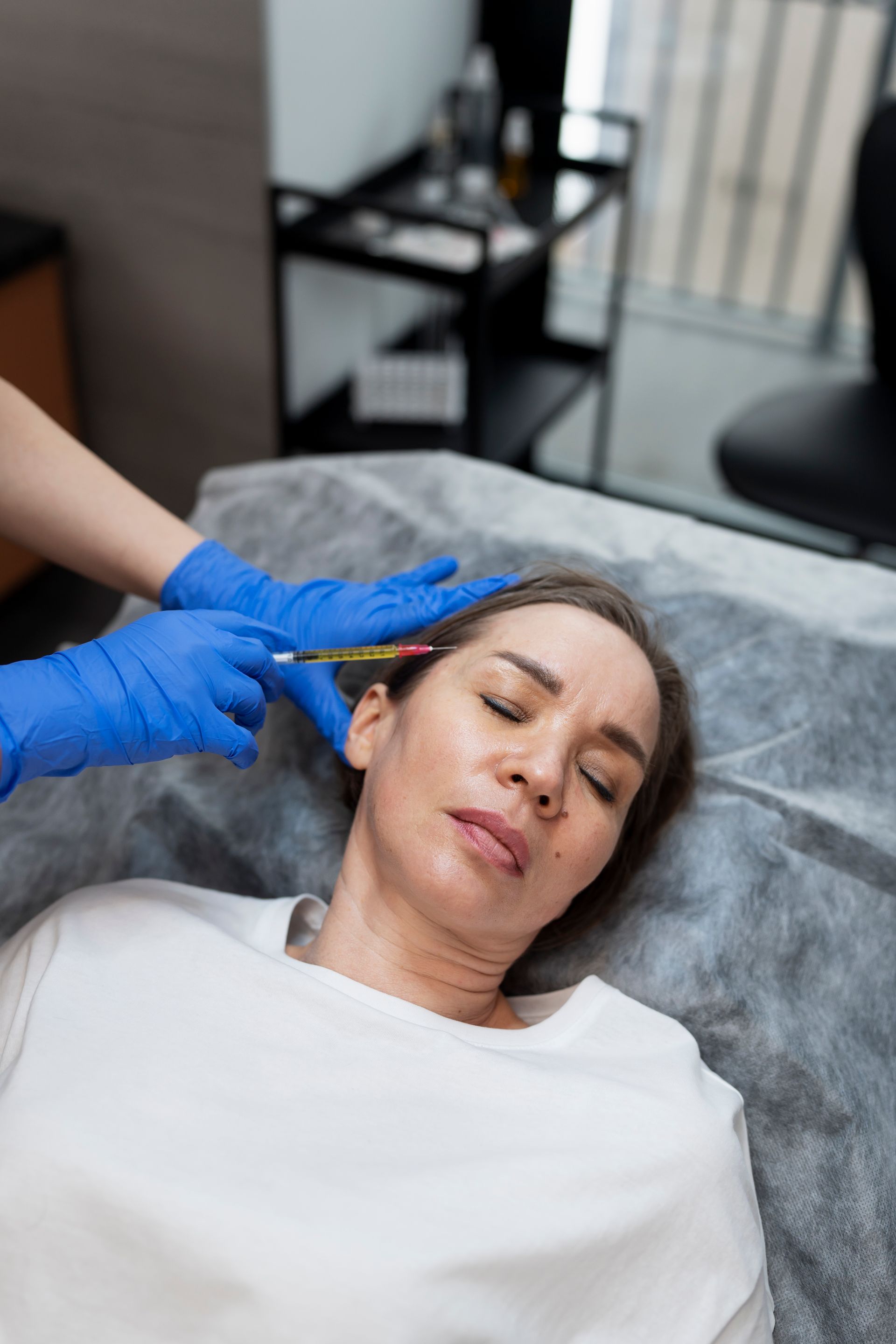 A woman is getting an injection in her face in a beauty salon.