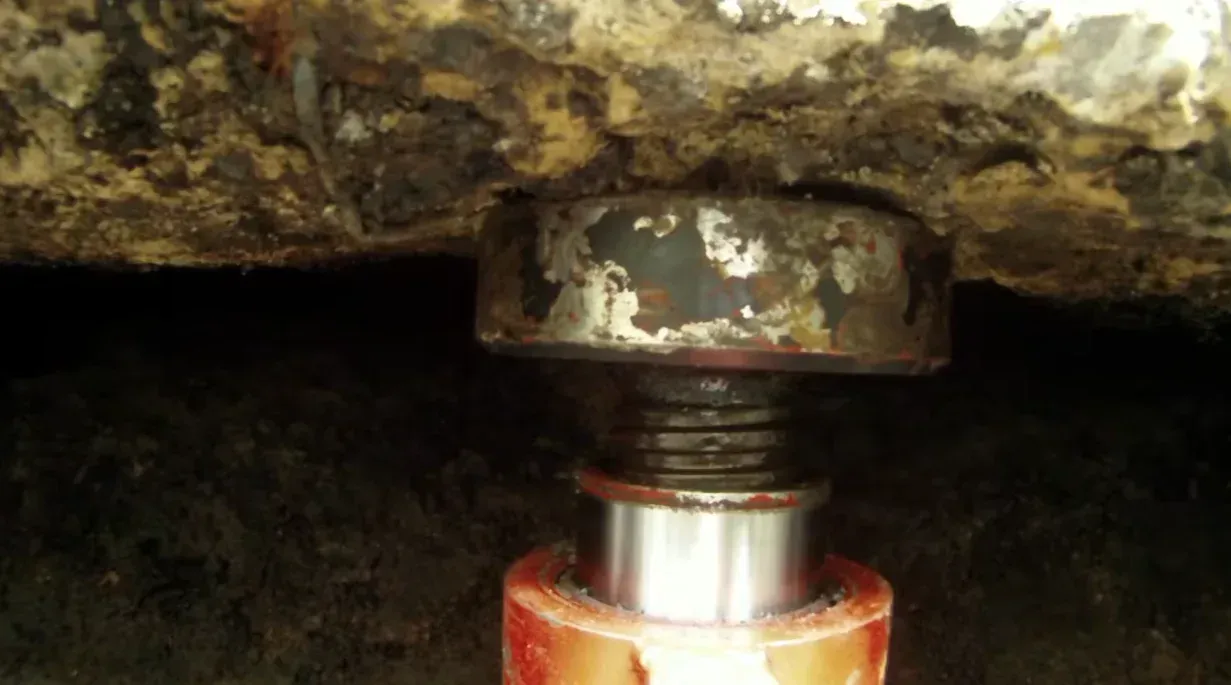 Close up of a hydraulic jack lifting a concrete foundation slab, a key part of understanding foundation and house raising costs