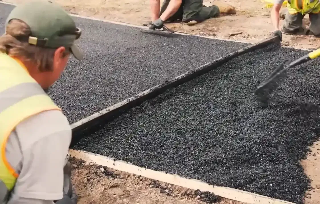 Construction crew leveling a porous concrete and aggregate mix demonstrating how water can seep through foundation materials