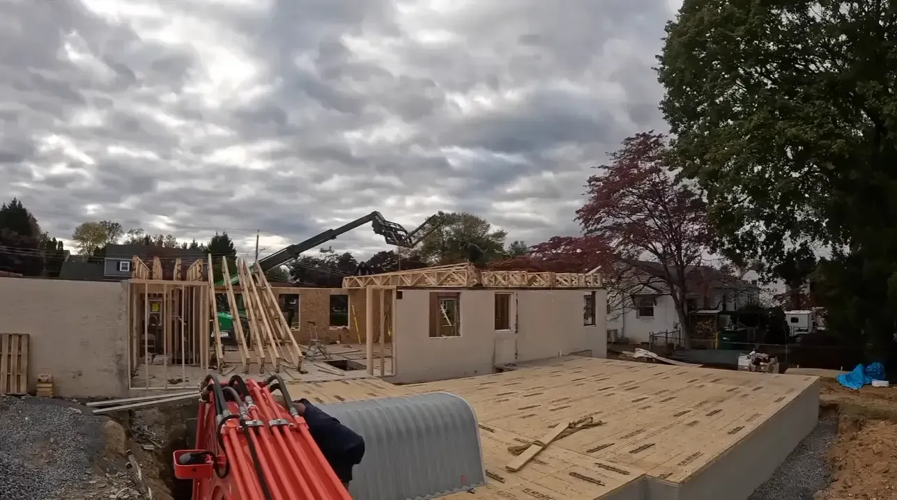 Crane lifting roof trusses onto new foundation walls during a residential construction project