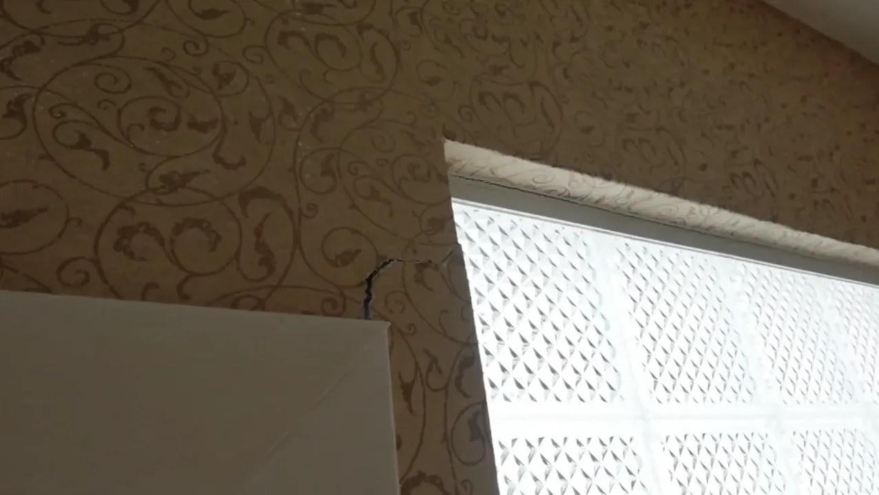 Diagonal wall crack near a window from foundation settling in an older home