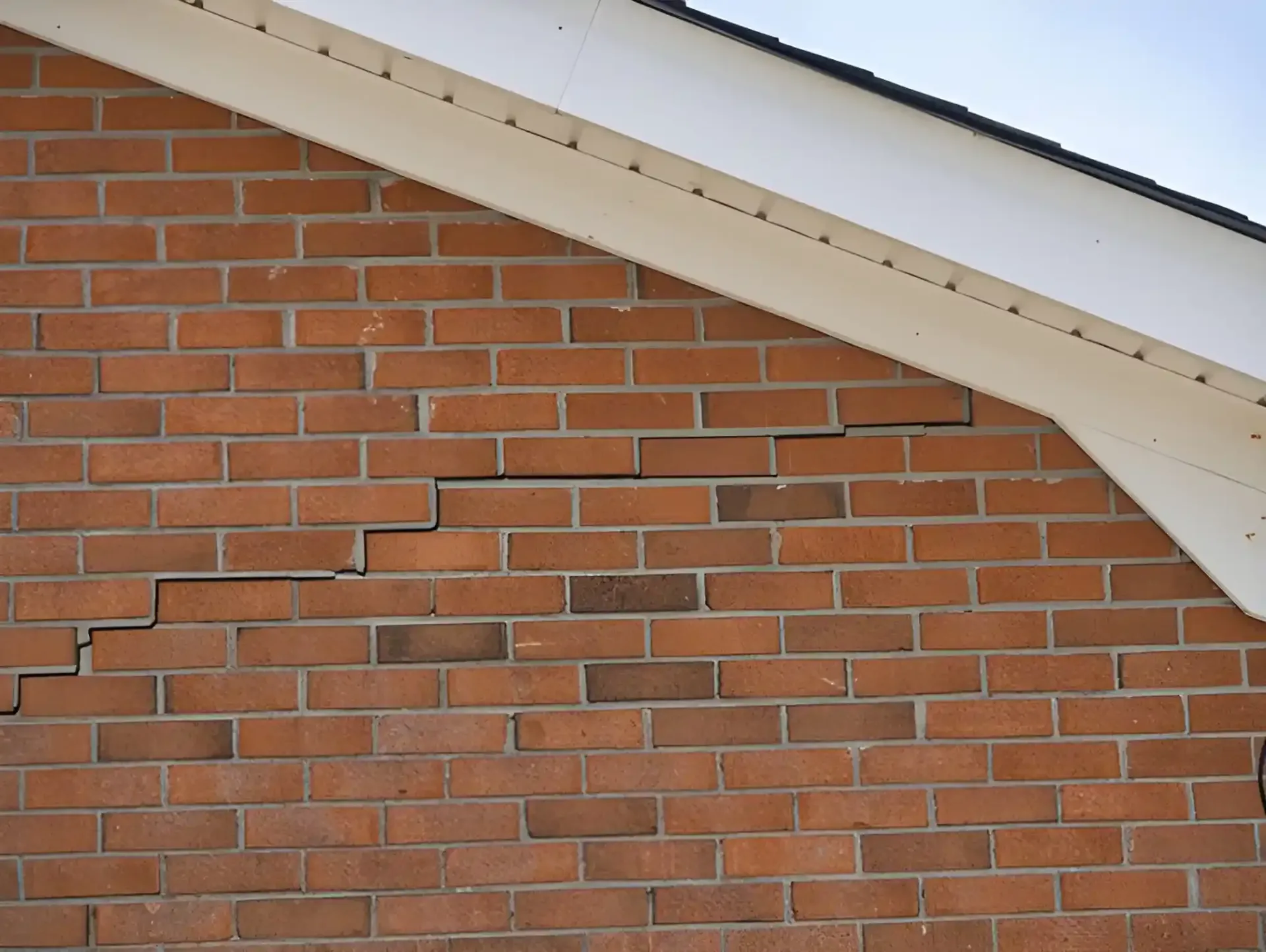 Exterior brick wall showing stair-step crack, a common sign of foundation settlement requiring professional repair.