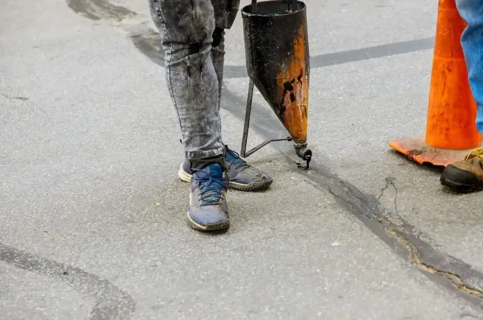 Foundation repair team sealing driveway cracks to stop water intrusion and protect against concrete settlement.