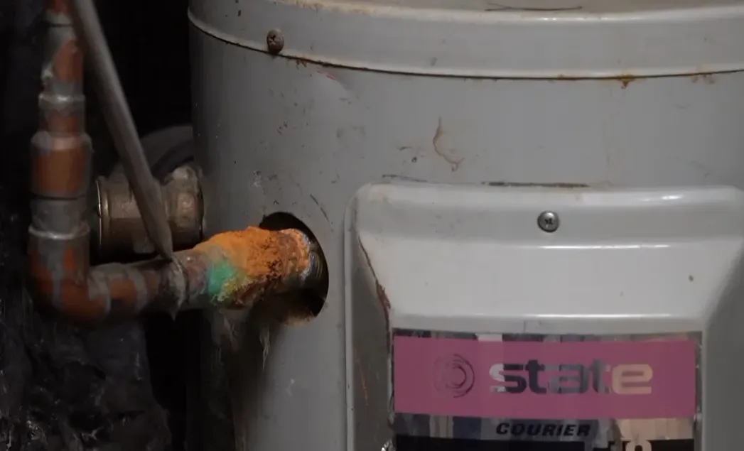 Heavily corroded copper pipe connection at a water heater showing the type of plumbing damage found during slab leak repair and detection