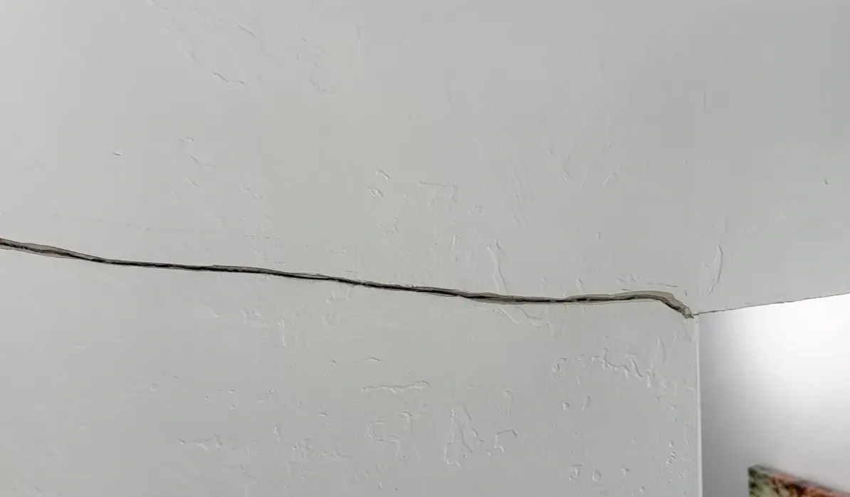 Horizontal crack running across an interior wall near the ceiling, a common sign a home needs wall crack repair and foundation stability evaluation