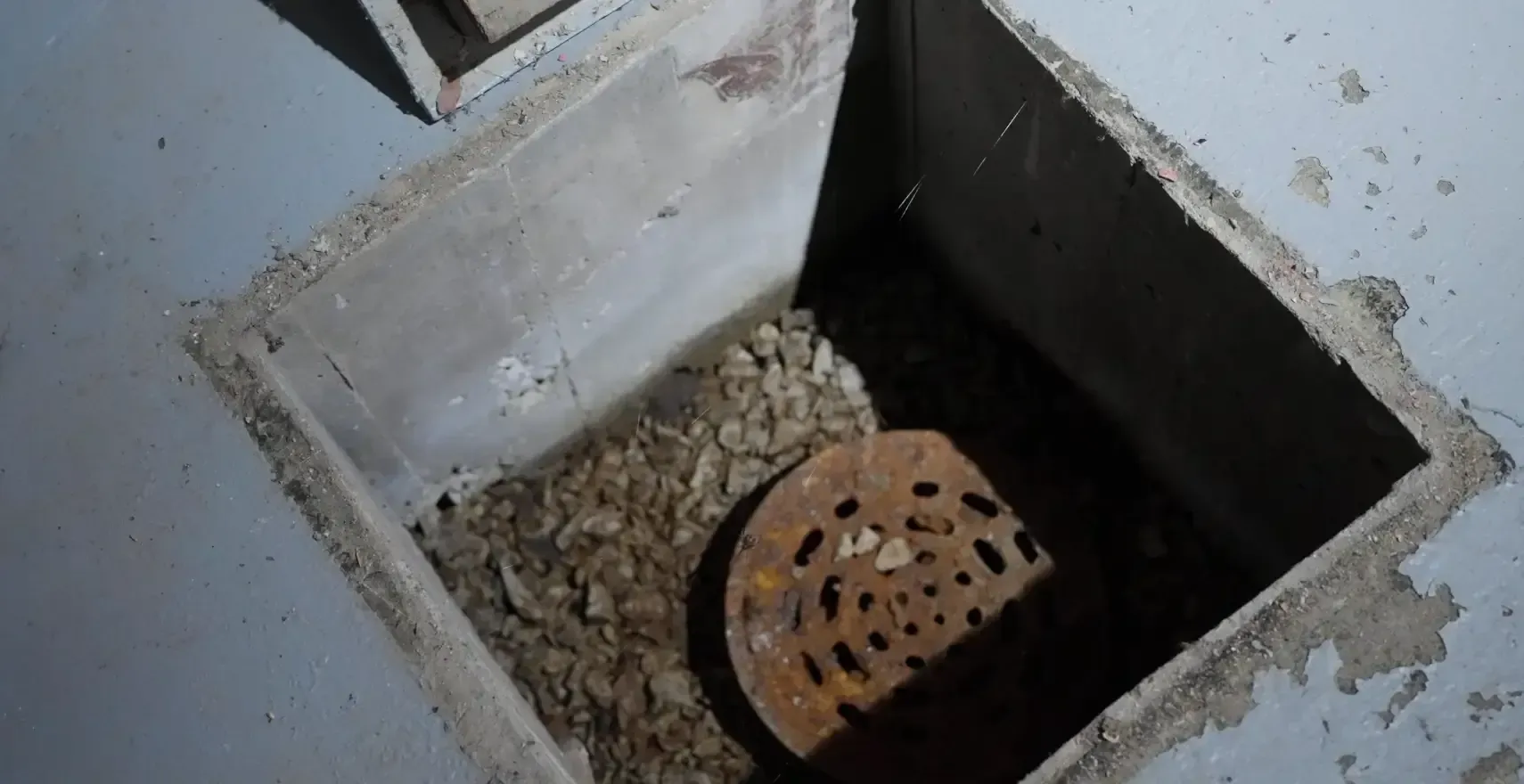 Open basement sump pit excavation with old rusted drain showing what is sump pit before replacement