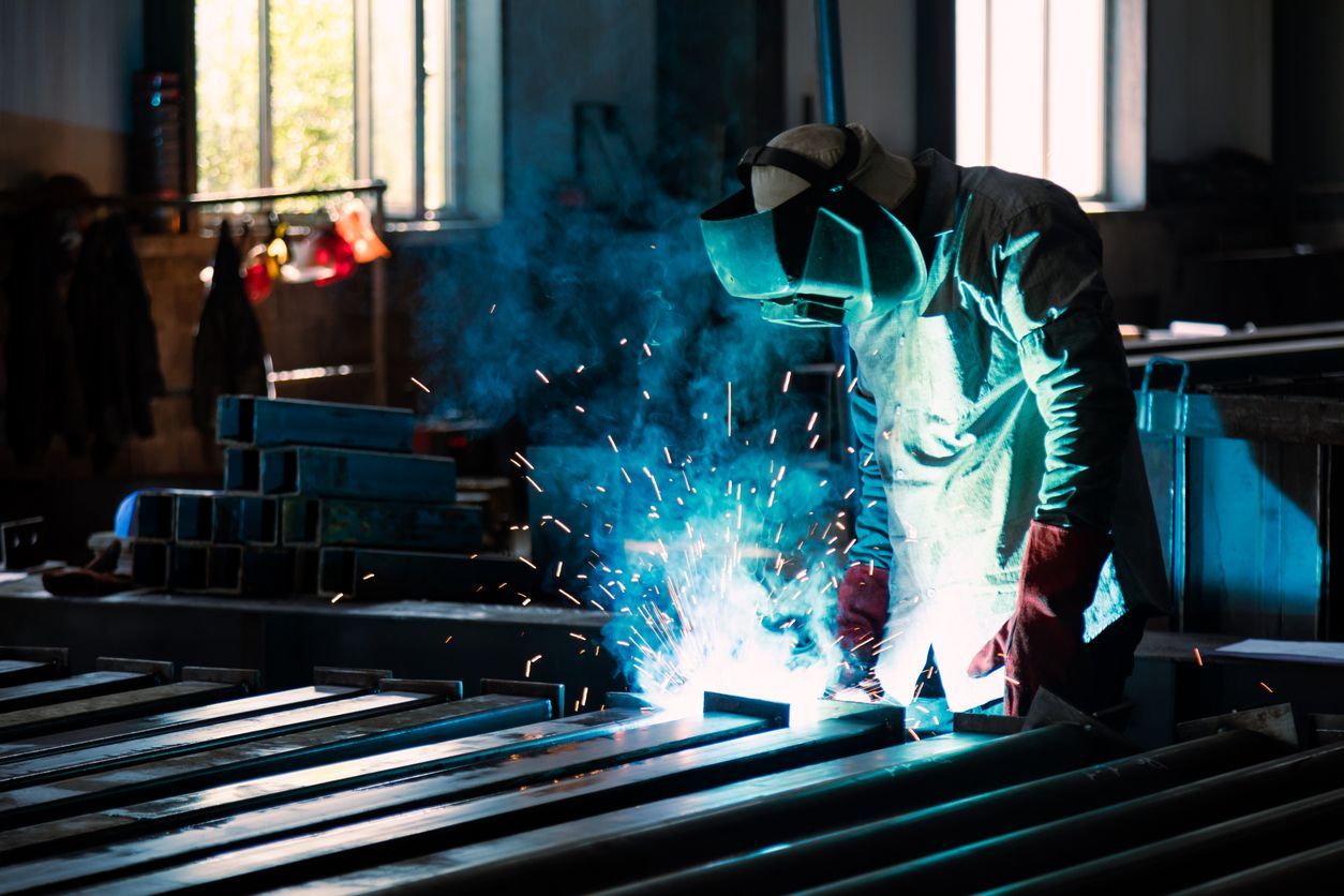 A man is welding a piece of metal in a factory.