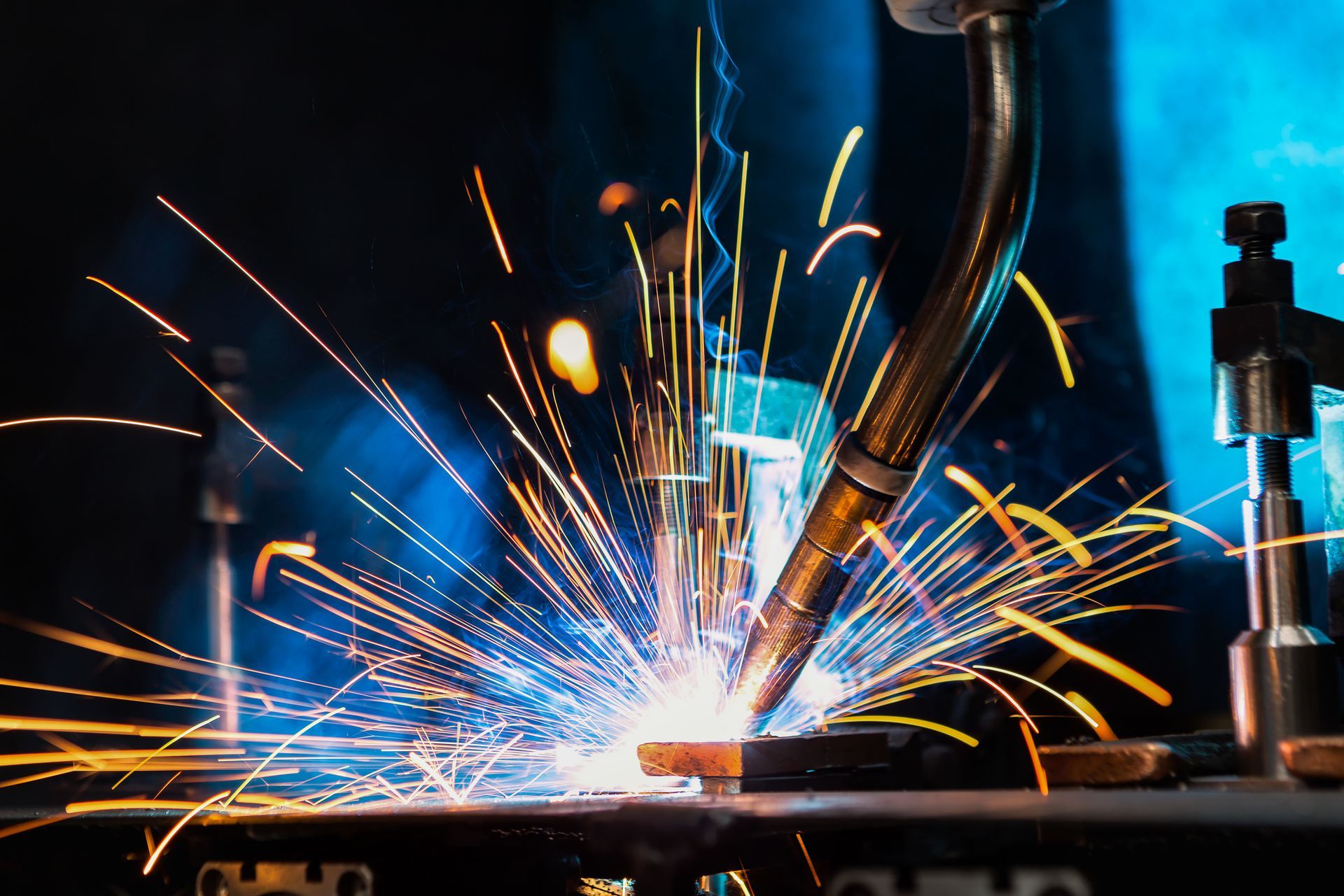 A man is welding a piece of metal in a factory.
