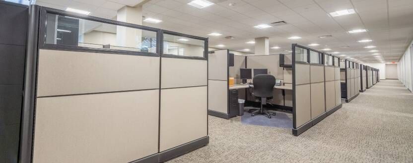 A row of cubicles in an office with a person sitting at a desk.