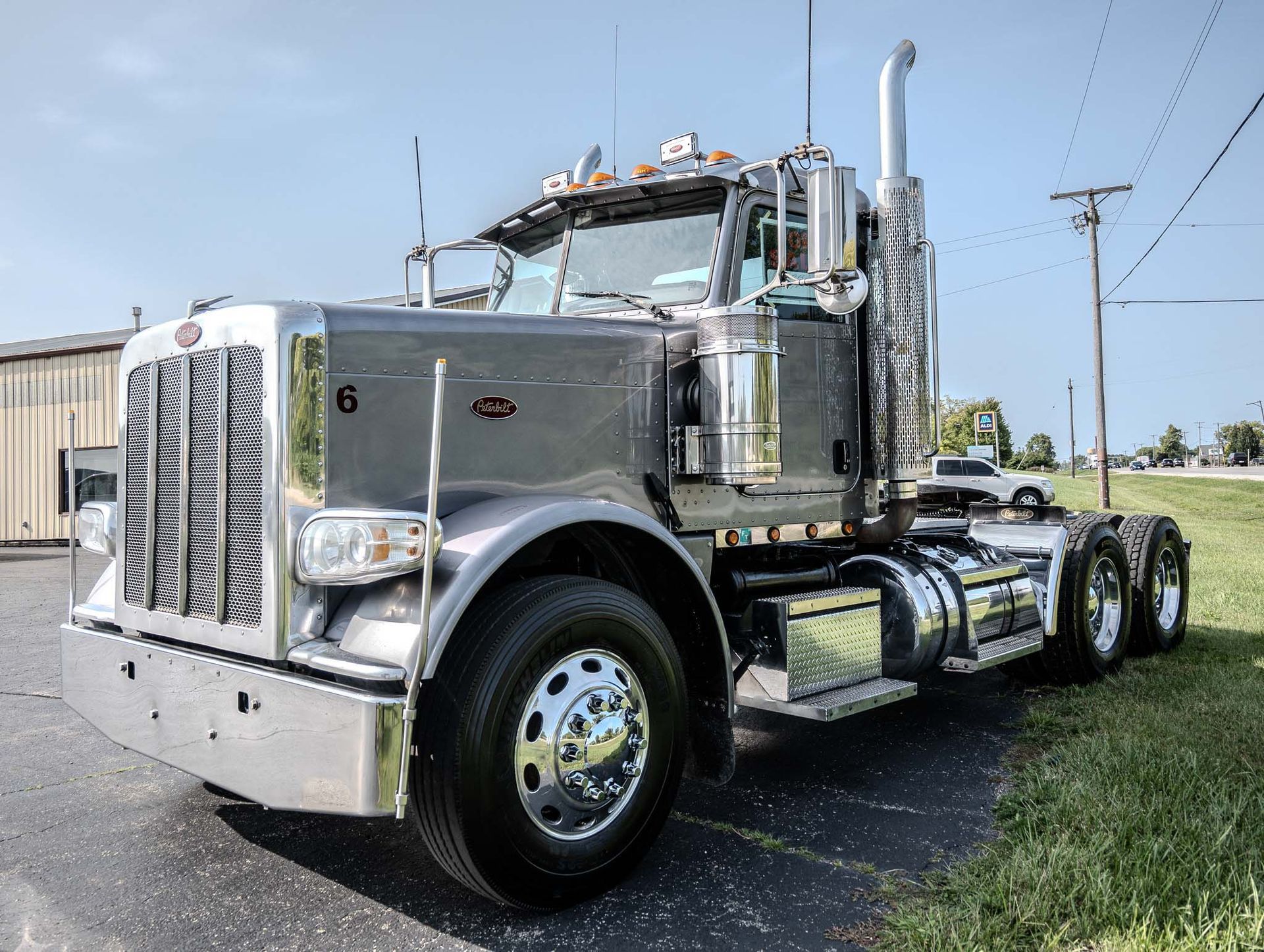 A silver semi truck is parked on the side of the road after fleet detailing.