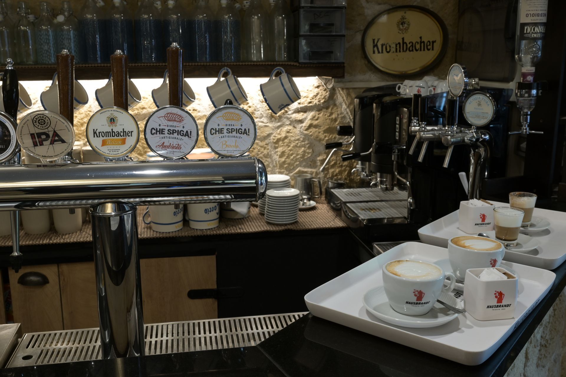 Bancone di caffetteria con macchina per espresso, barattoli etichettati e tazze su un vassoio