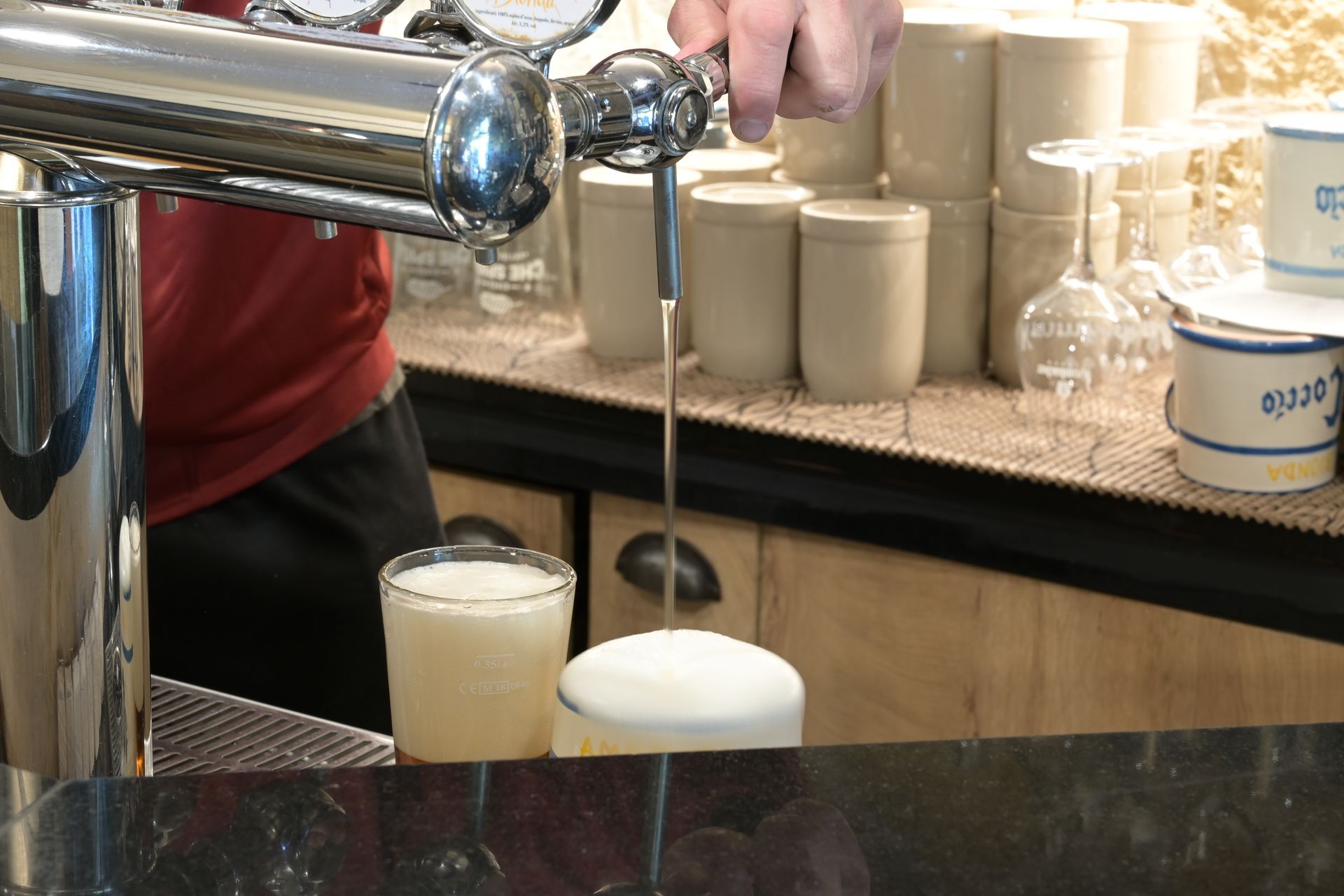 Birra spillata alla spina in un bicchiere schiumoso sul bancone di un bar.