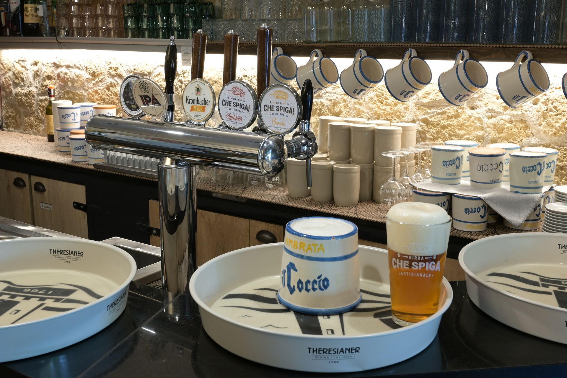 Buffet della colazione con piatti, tazze e un boccale da birra impilati accanto a un banco del cibo