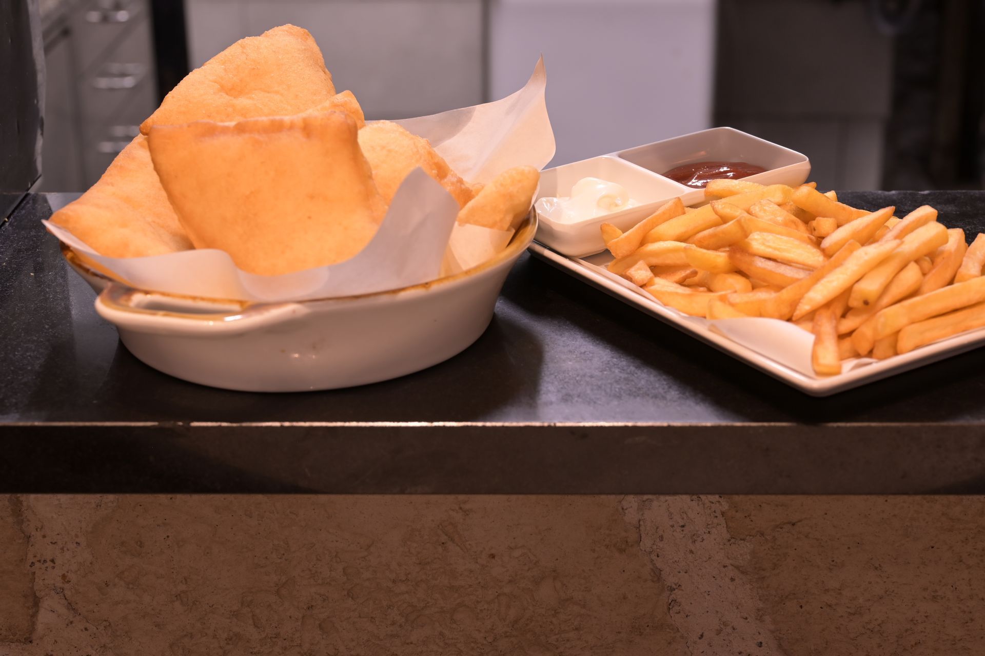 Ciotola di nachos e vassoio di patatine fritte su un bancone