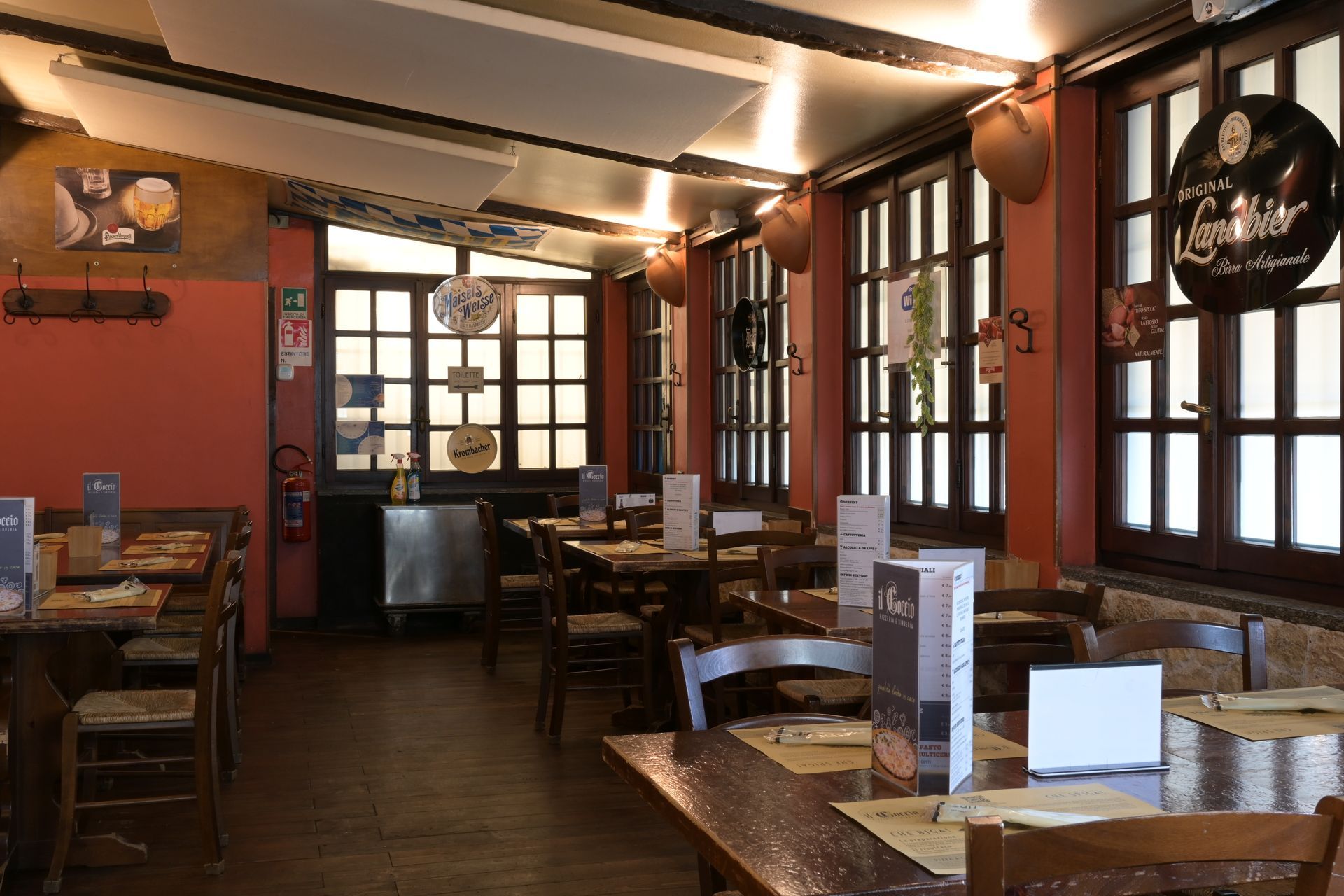 Accogliente interno di ristorante con tavoli in legno, illuminazione calda e grandi finestre
