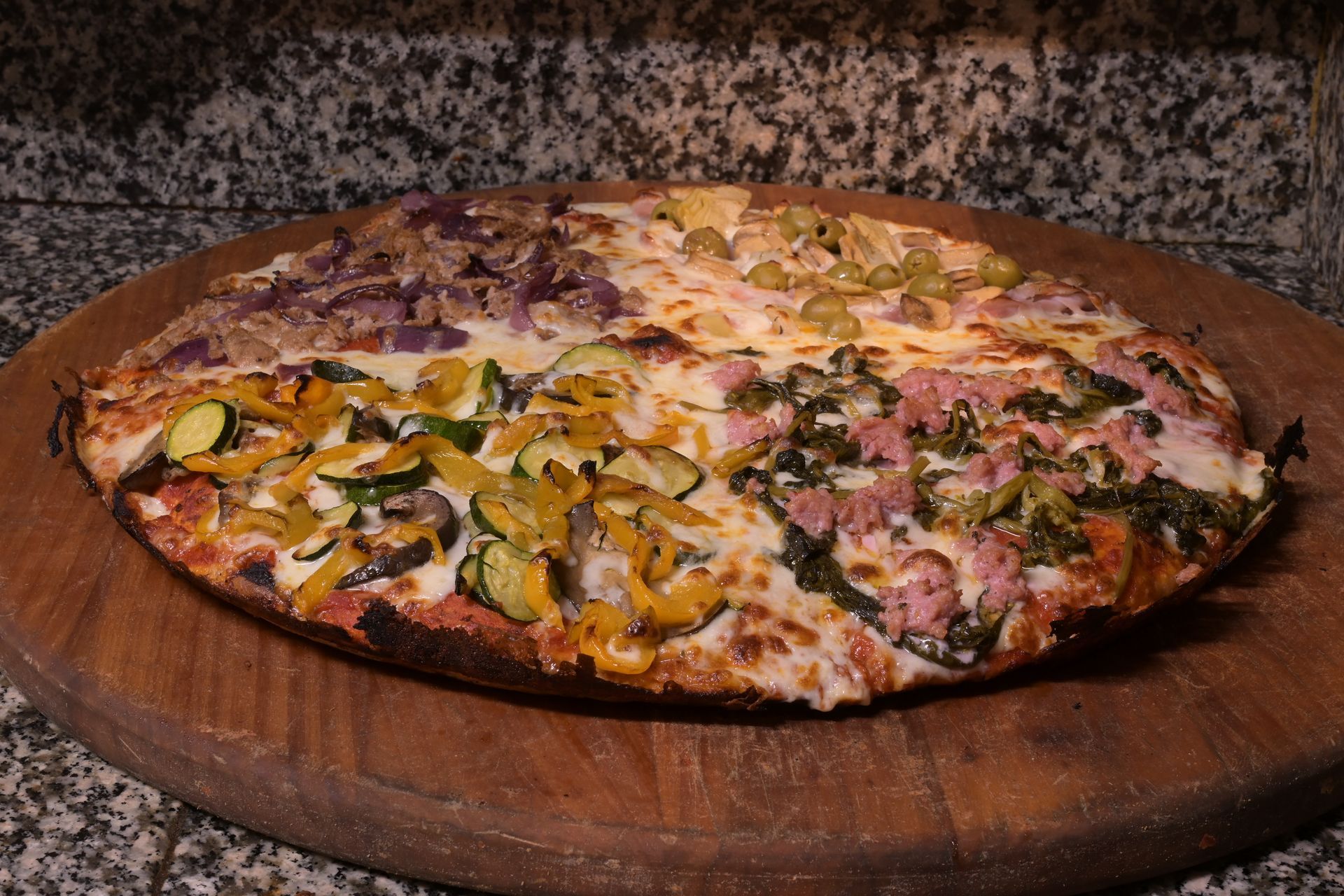 Pizza grande con verdure e prosciutto su un tagliere di legno, ripresa da vicino