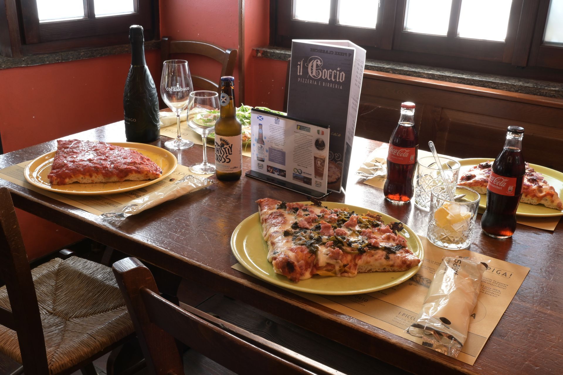 Due pizze e bevande su un tavolo di legno al ristorante, vicino alla finestra.