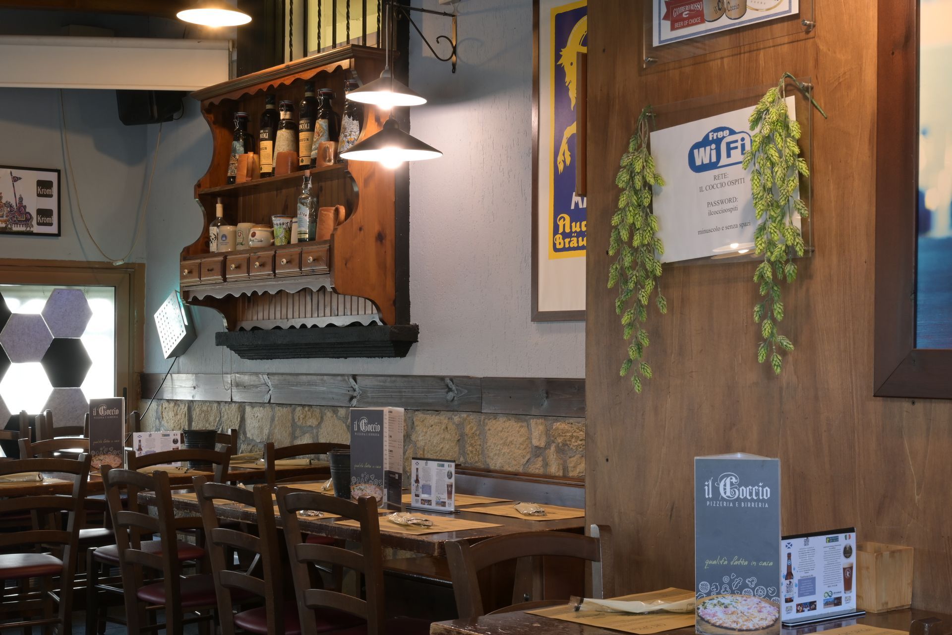 Accogliente interno di ristorante con tavoli in legno, lampade a sospensione, decorazioni alle pareti e un piccolo leggio con il menu