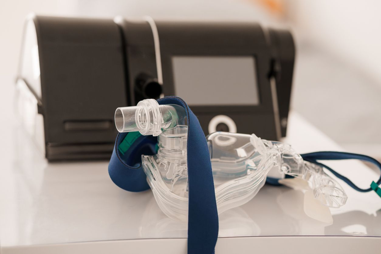 Clear medical breathing mask and tubing on a table beside a dark case