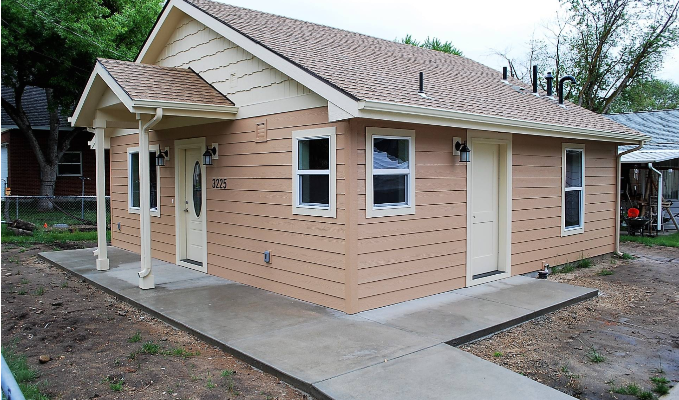 Front view of a craftsman-style house with a red front door and a covered porch.