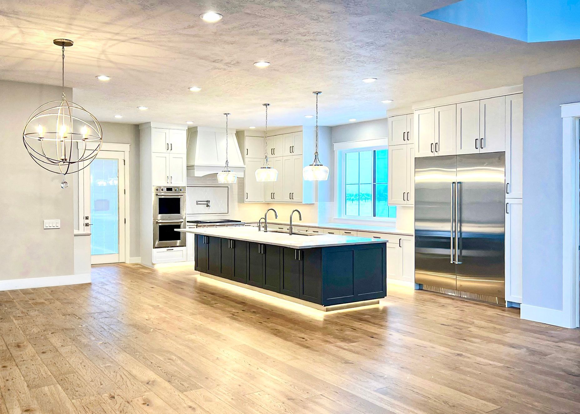 Modern kitchen with wood cabinets, island, sink, stove, and turquoise glass decor on the counter