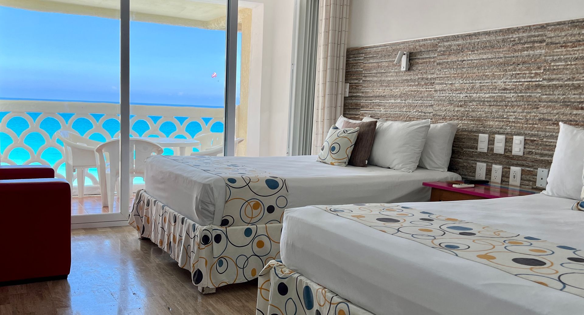 Habitación de hotel con dos camas y balcón con vistas al mar. Combinación de colores azul, blanco y marrón.