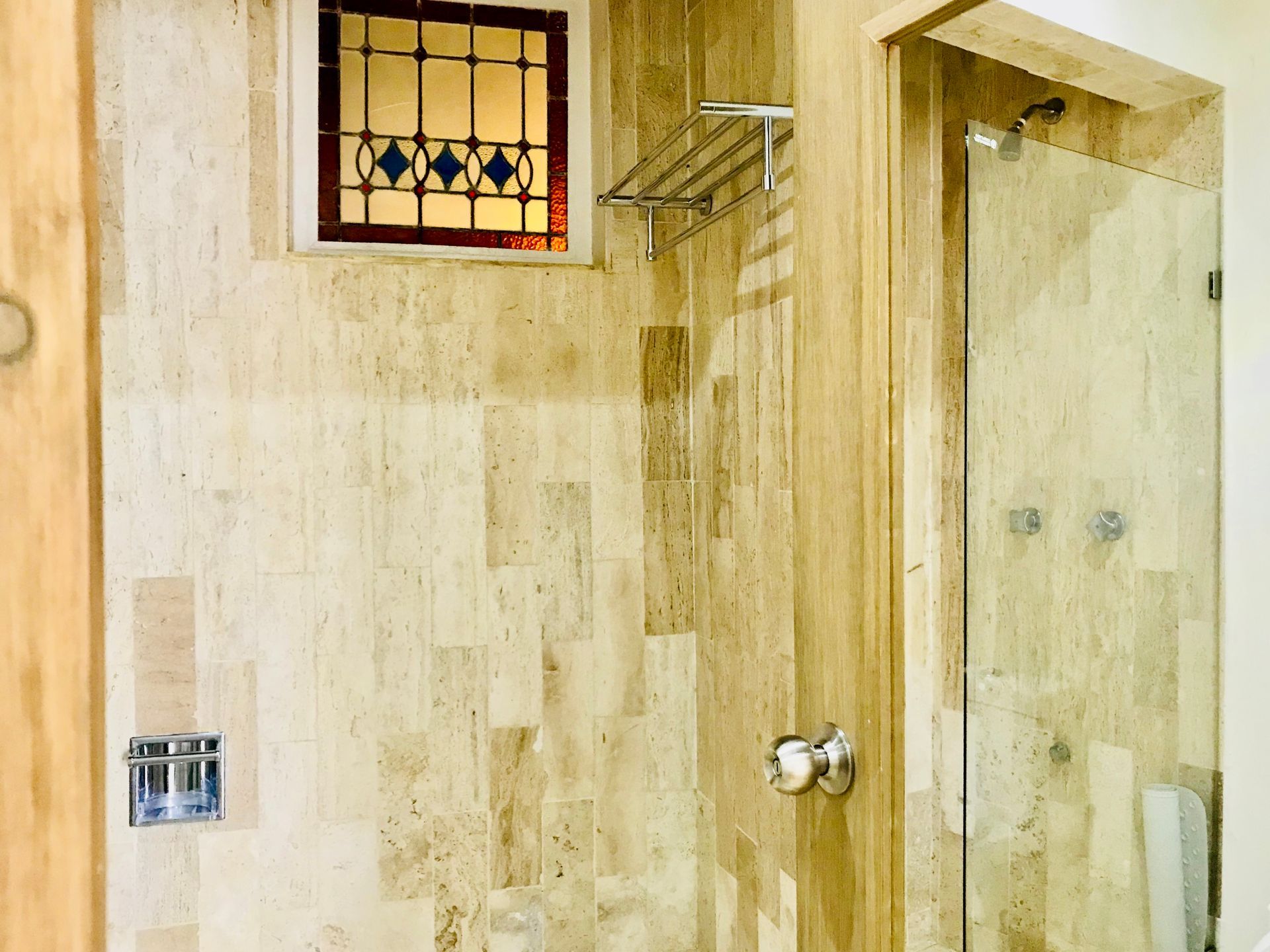 Ducha de baño con paredes alicatadas, puerta de cristal, vidriera y toallero.