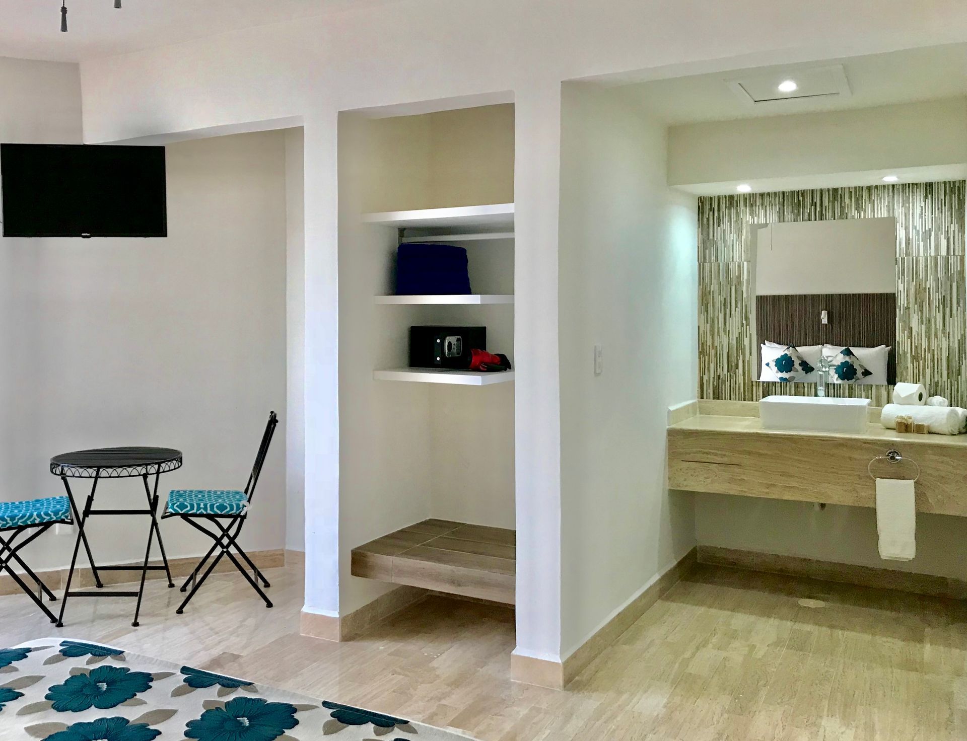 Dormitorio con TV, mesa y sillas, armario y baño con lavabo.