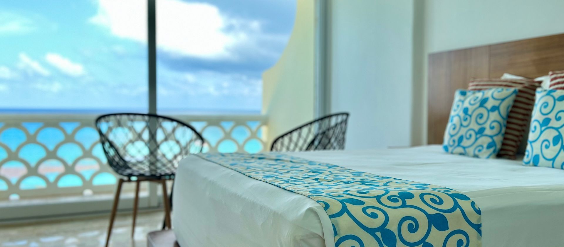 Un dormitorio de hotel con cama, sillas y vista al mar.