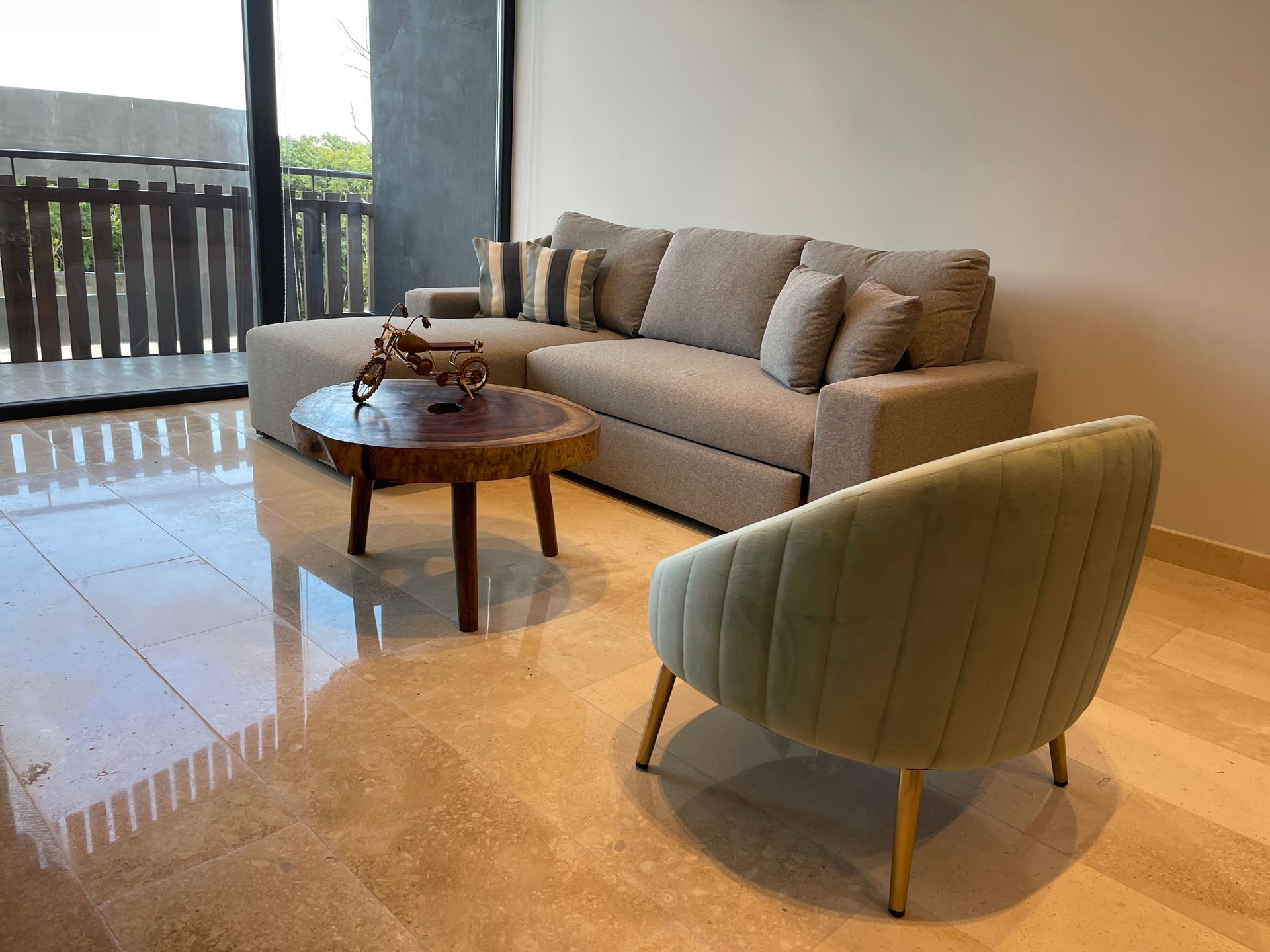 Sala de estar con sofá seccional beige, mesa de centro de madera y sillón verde claro.