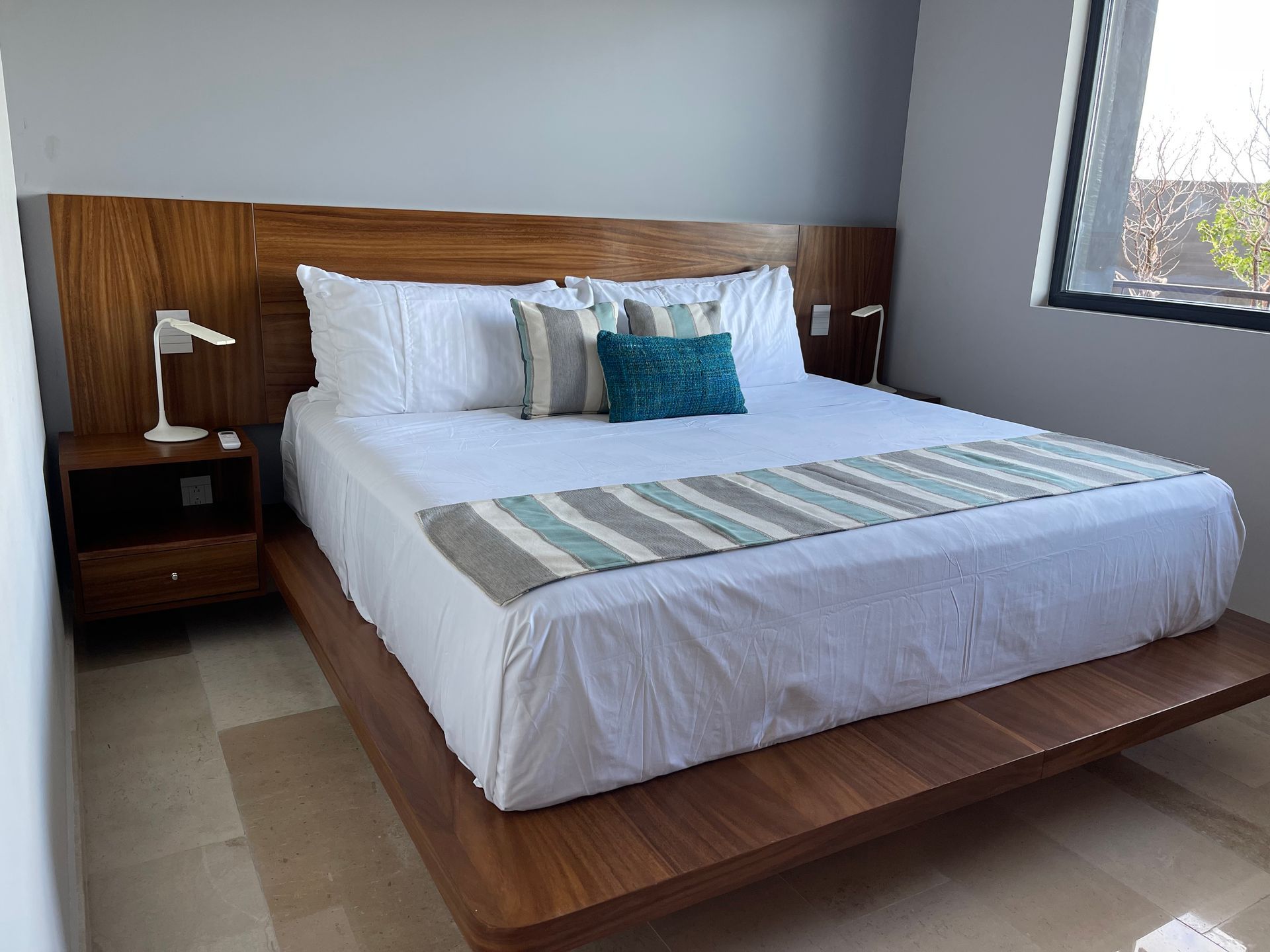Dormitorio con una gran cama de madera, sábanas blancas y almohadas decorativas.