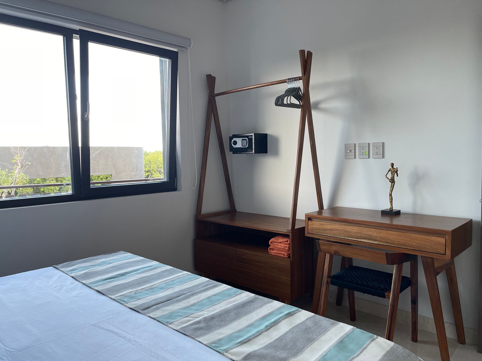 Dormitorio con muebles de madera, ventana, cama y caja fuerte en la pared.