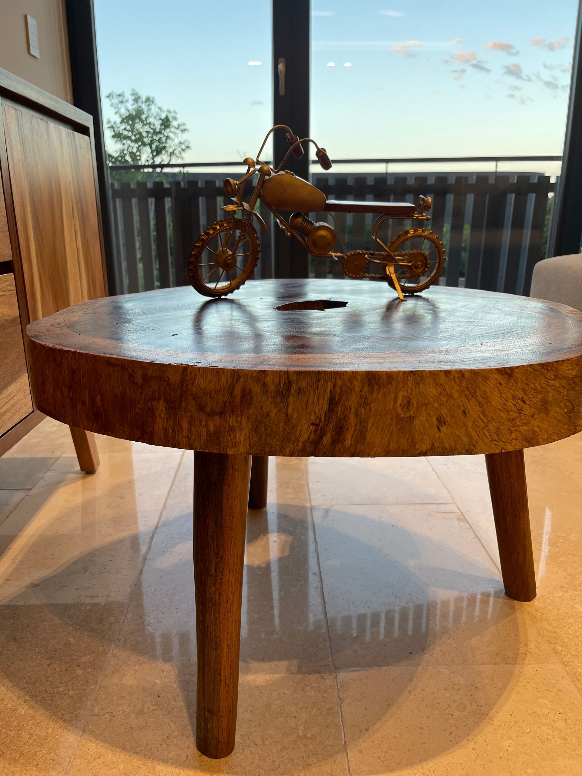 Mesa de centro de madera con escultura decorativa de motocicleta.