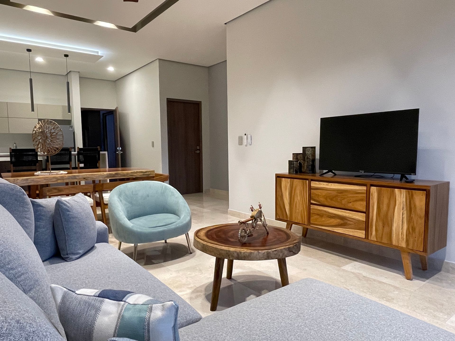 Sala de estar con sofá azul, muebles de madera y TV.