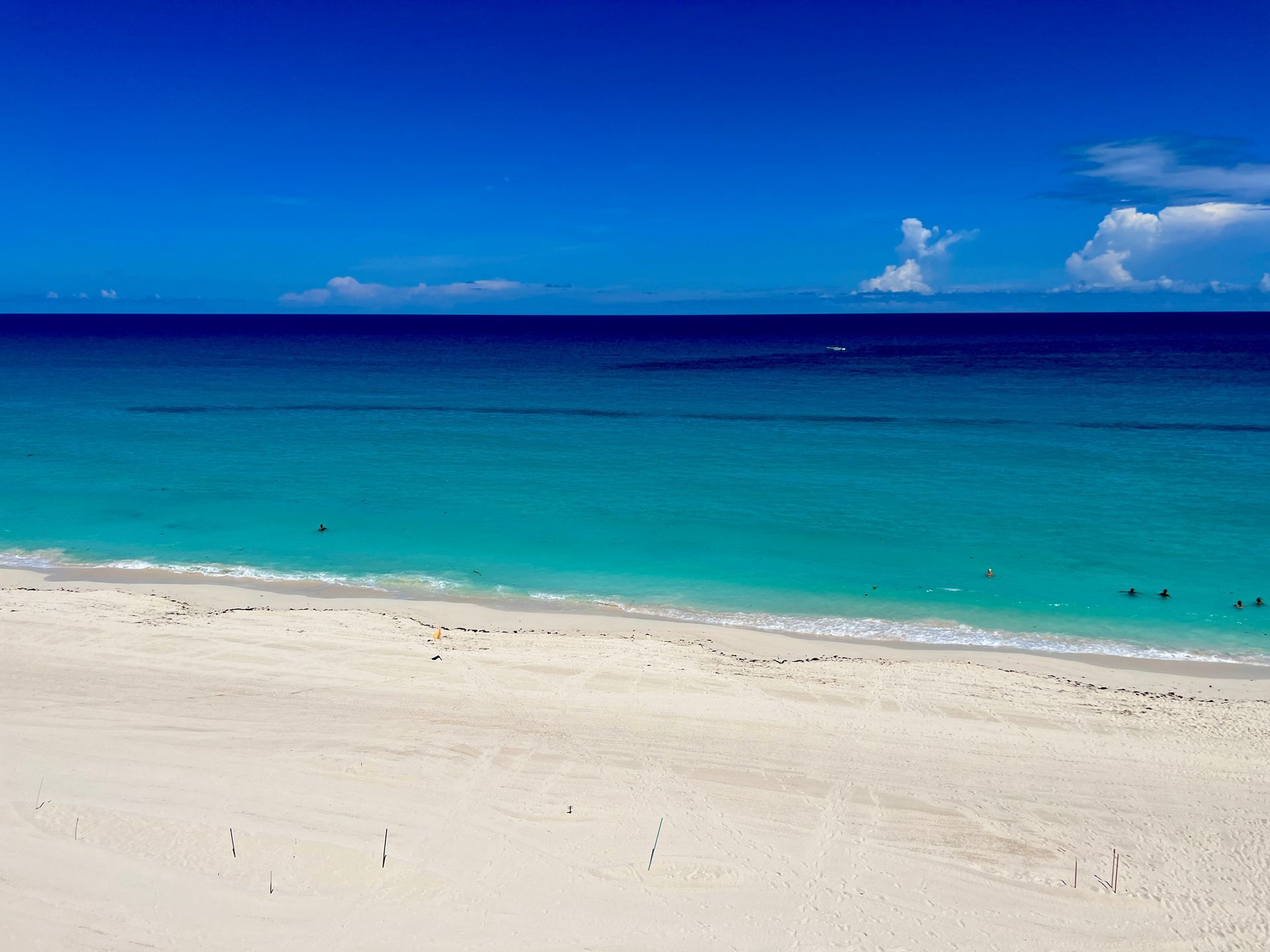 Bright blue sky over turquoise ocean meeting a white sandy beach.