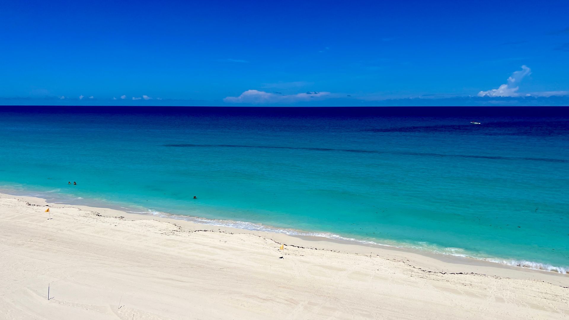 Cielo azul brillante sobre el océano turquesa y la playa de arena blanca.